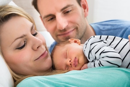 39435510 - close-up of two parents looking at newborn sleeping baby